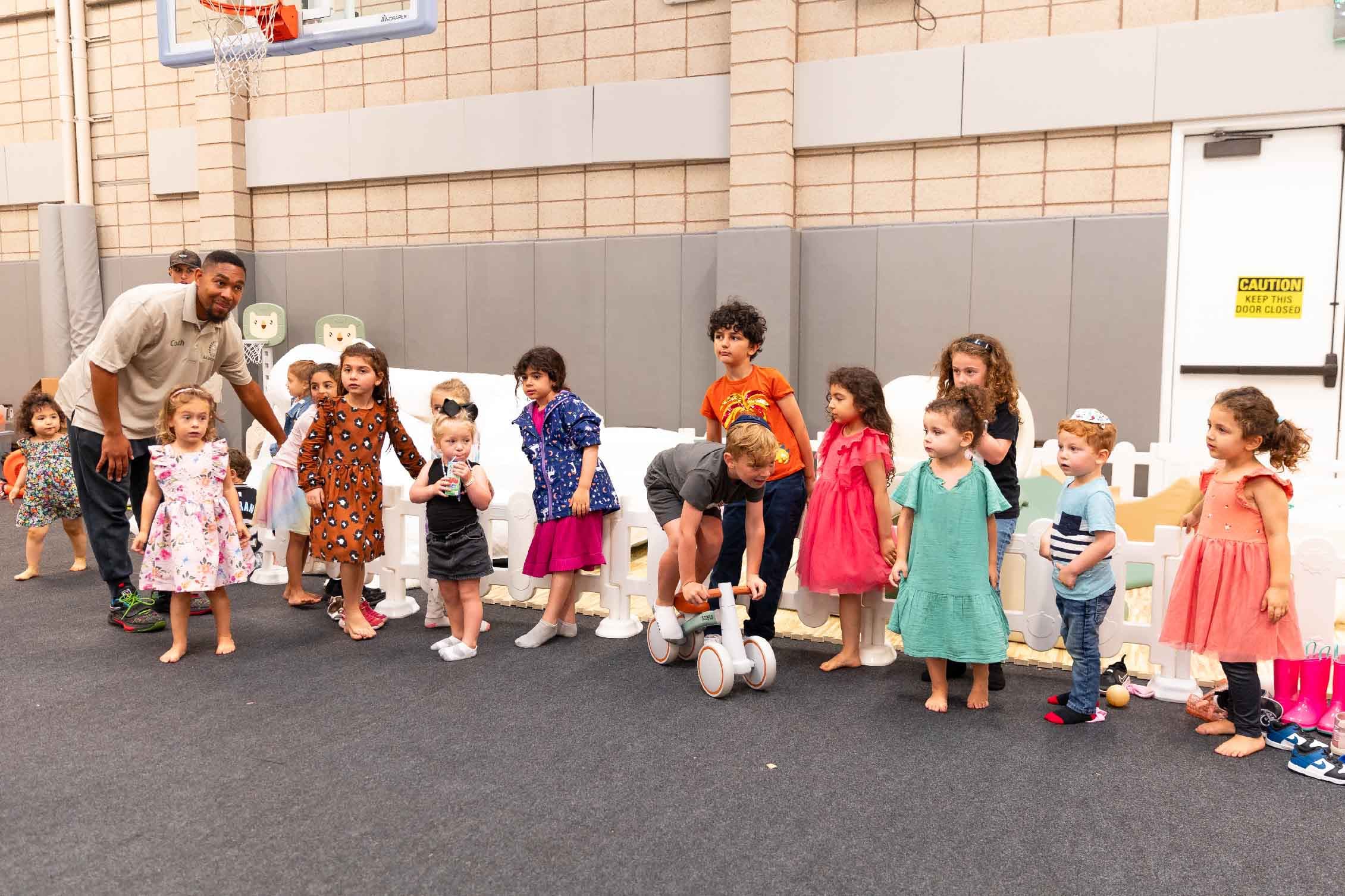Young children lining up with an LA Sports World coach in a gym